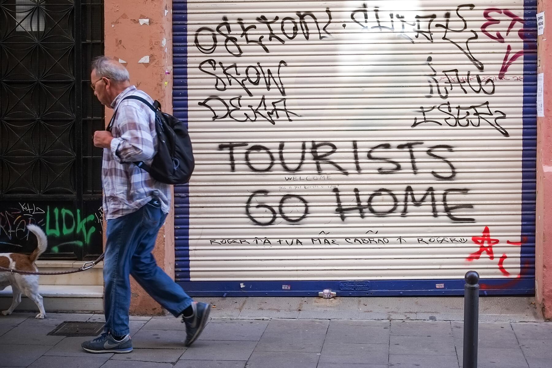 3_Barcelona, Spain, June 15th 2024 man walks, passing by a graffiti_Shutterstock_2490399313